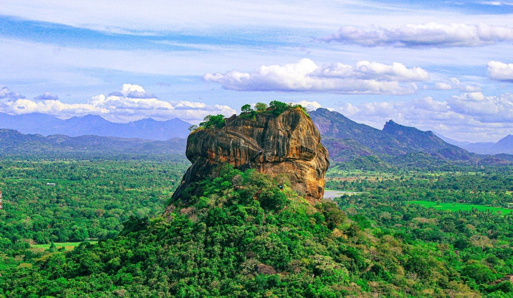 How to Get to Sigiriya from Colombo: Car, Train or Bus Sigiriya Rock Fortress rising above green forest with the Knuckles hills behind