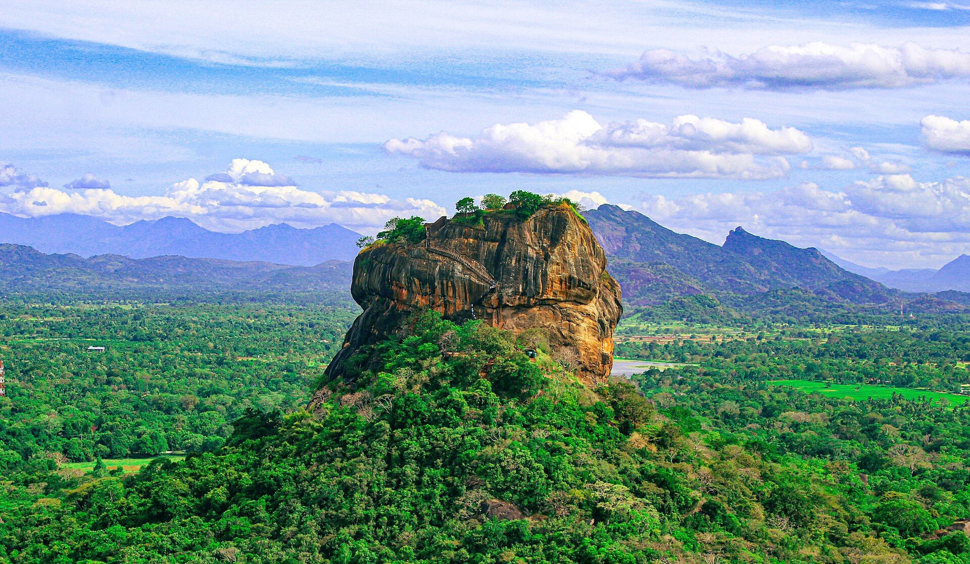 How to Get to Sigiriya from Colombo: Car, Train or Bus Sigiriya Rock Fortress rising above green forest with the Knuckles hills behind