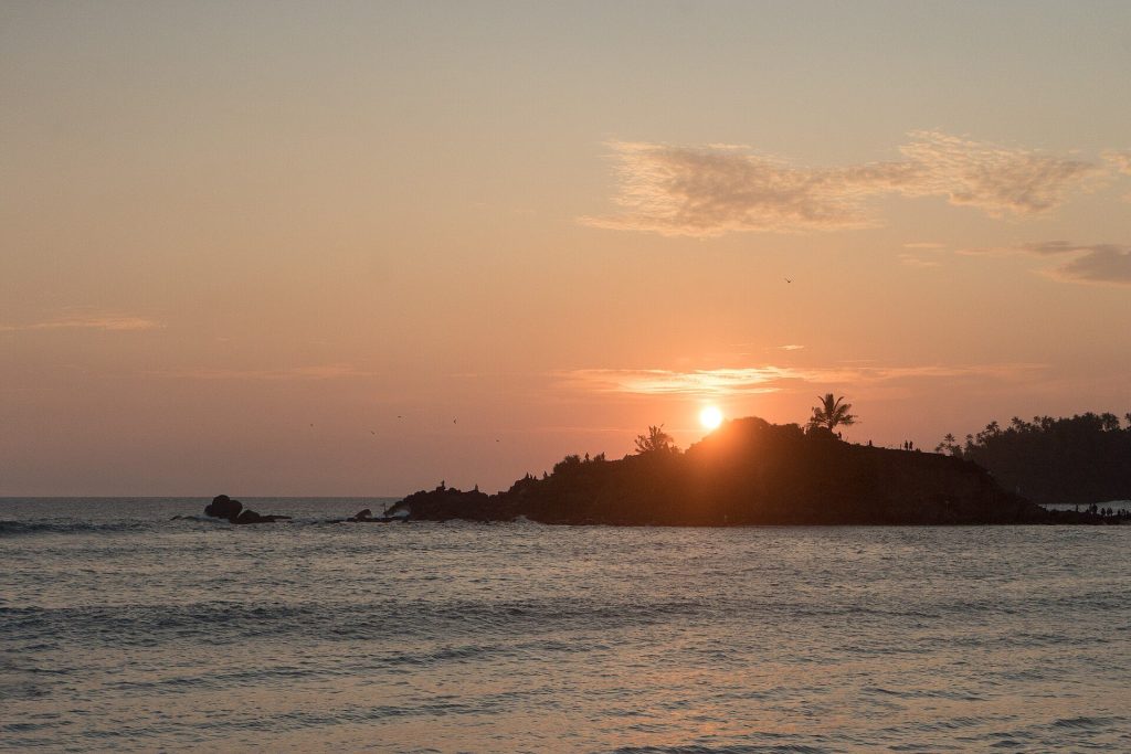 Sun setting behind Parrot Rock in Mirissa, Sri Lanka