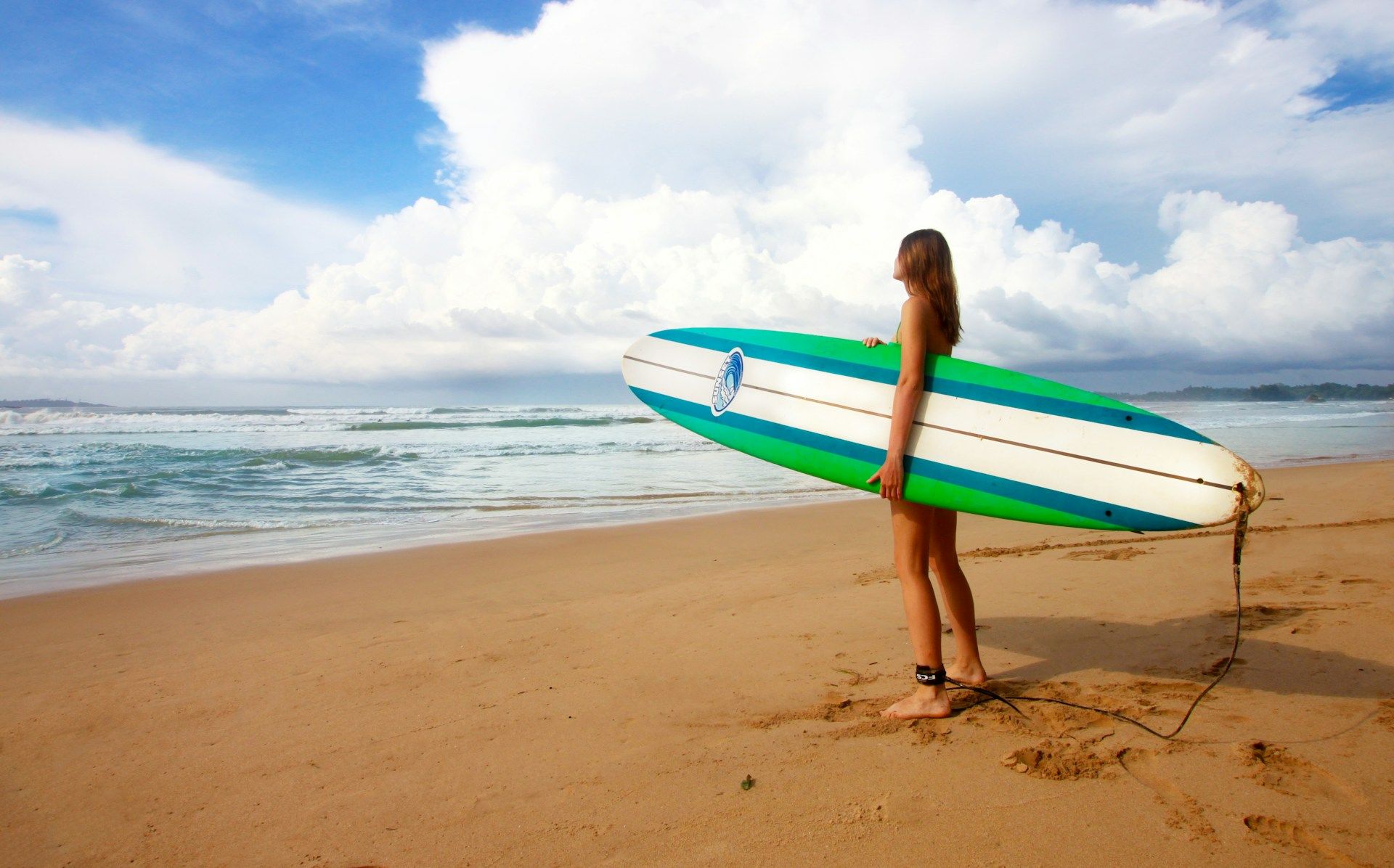 Surfer holding a surfboard on a sandy beach