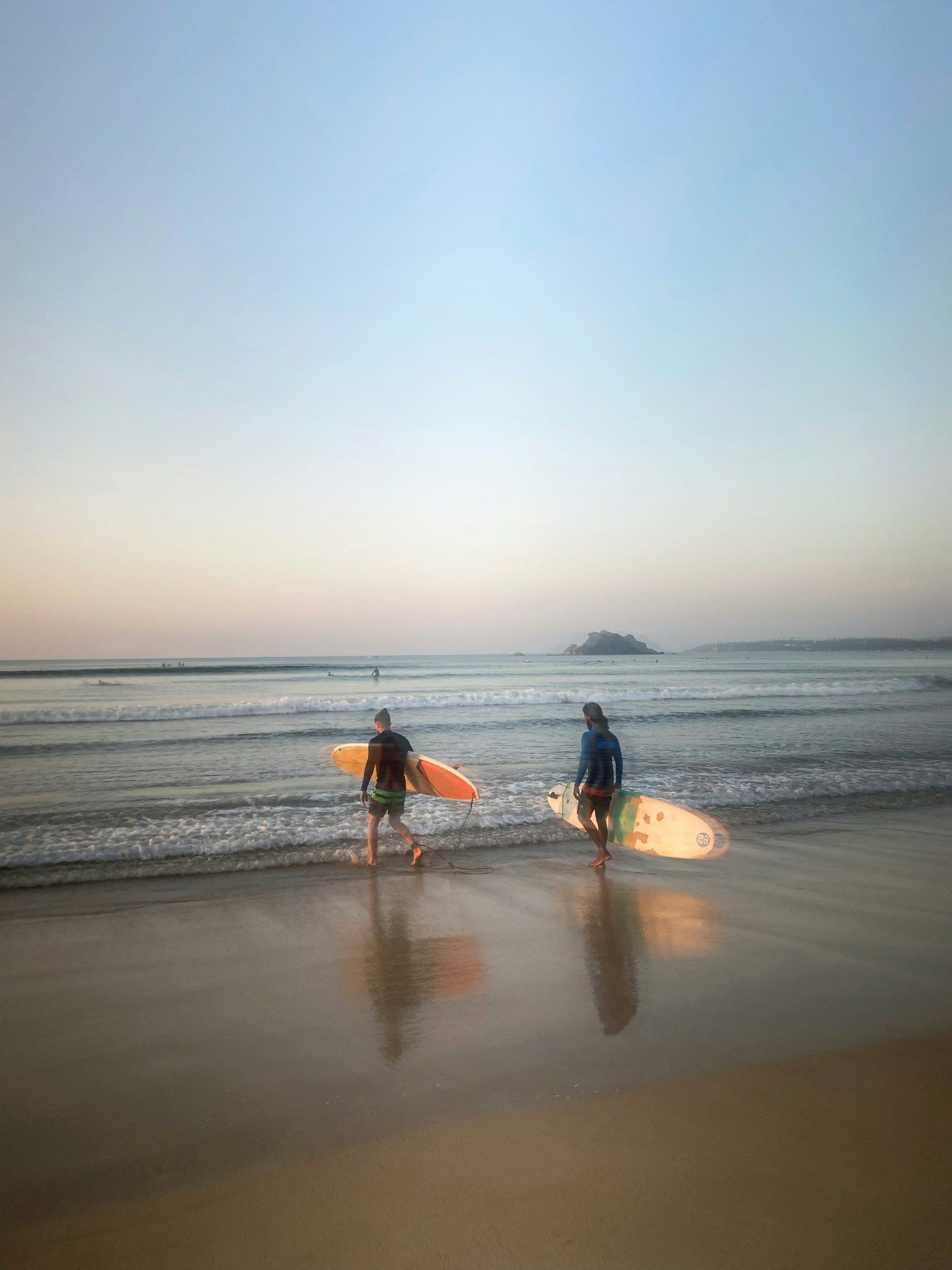 Two surfers carrying their boards into the sea